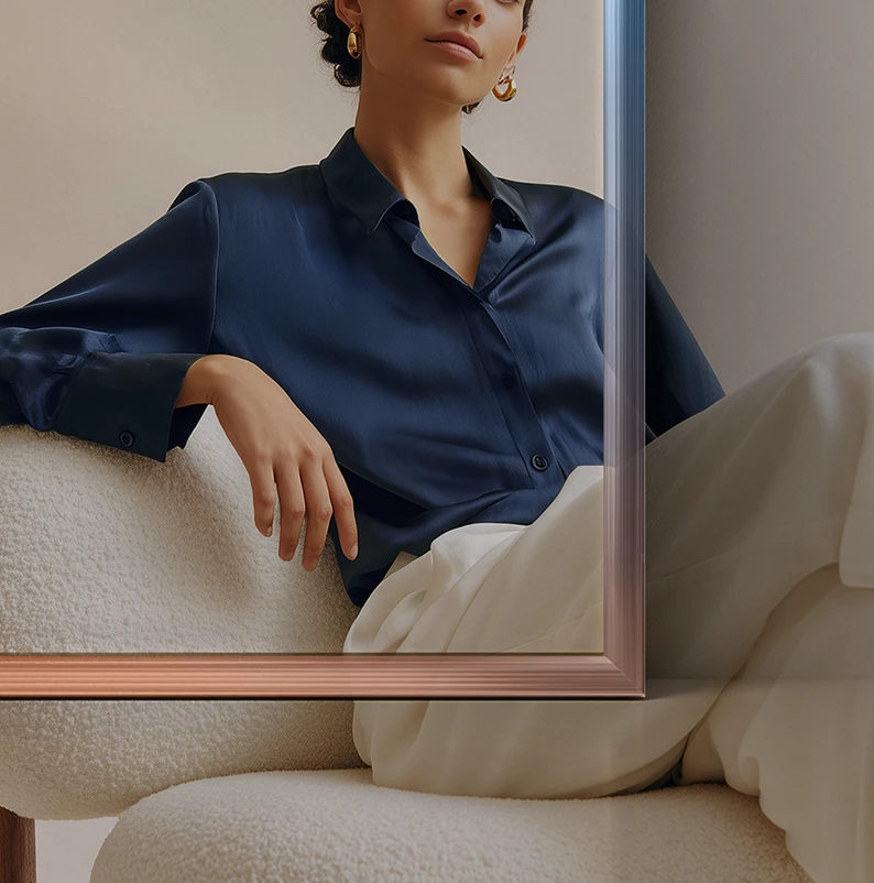 Donna seduta su una poltrona bianca, con camicia blu scuro e pantaloni chiari, indossa orecchini a cerchio dorati.